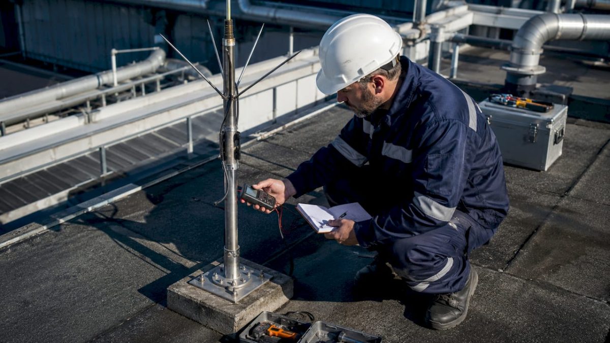 Un contrôleur effectue une vérification sur un paratonnerre installé dans une zone industrielle.