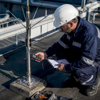 Un contrôleur effectue une vérification sur un paratonnerre installé dans une zone industrielle.