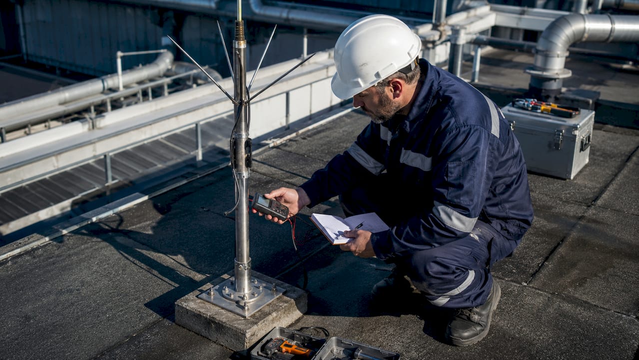 Un contrôleur effectue une vérification sur un paratonnerre installé dans une zone industrielle.