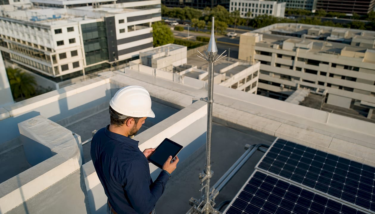 Un technicien effectue une inspection du paratonnerre installé sur le toit d’un bâtiment industriel.