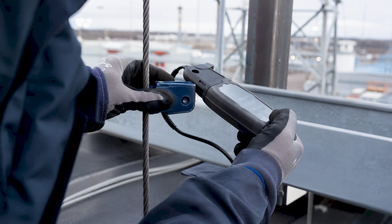 Un technicien, équipé de gants de protection, vérifie le bon fonctionnement du conducteur de terre à l’extérieur.