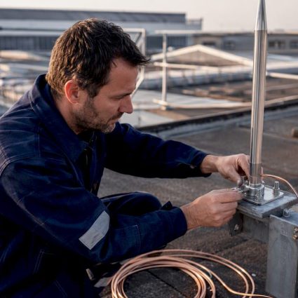 Technician installing lightning rod on rooftop