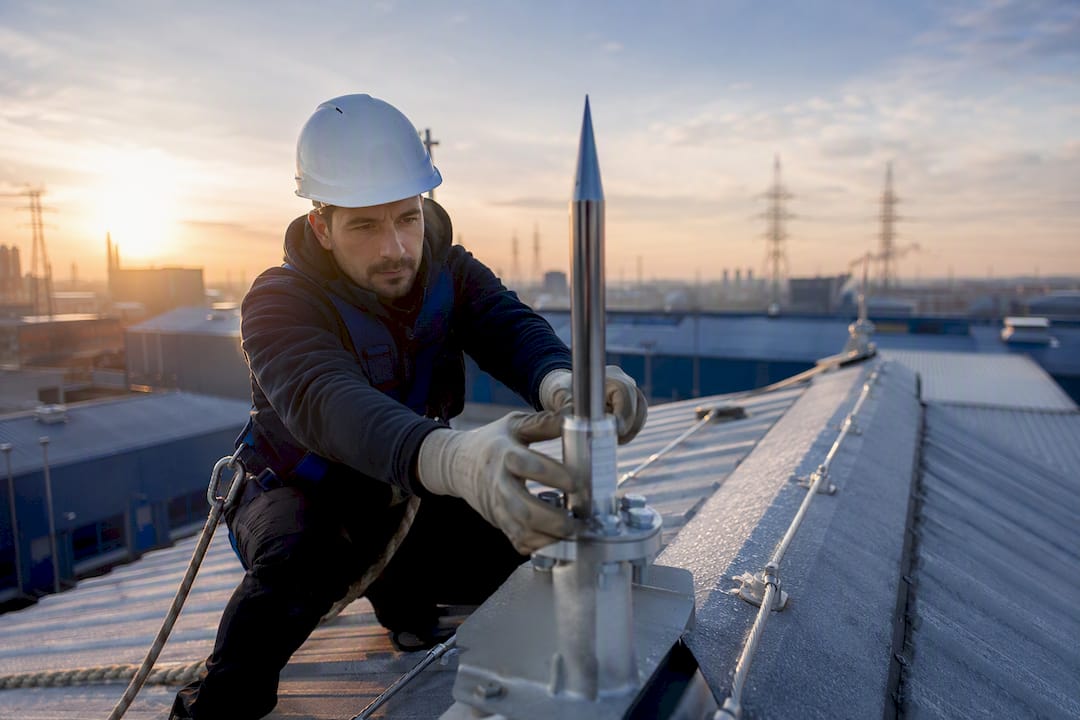 Technician installing lightning rod on industrial rooftop