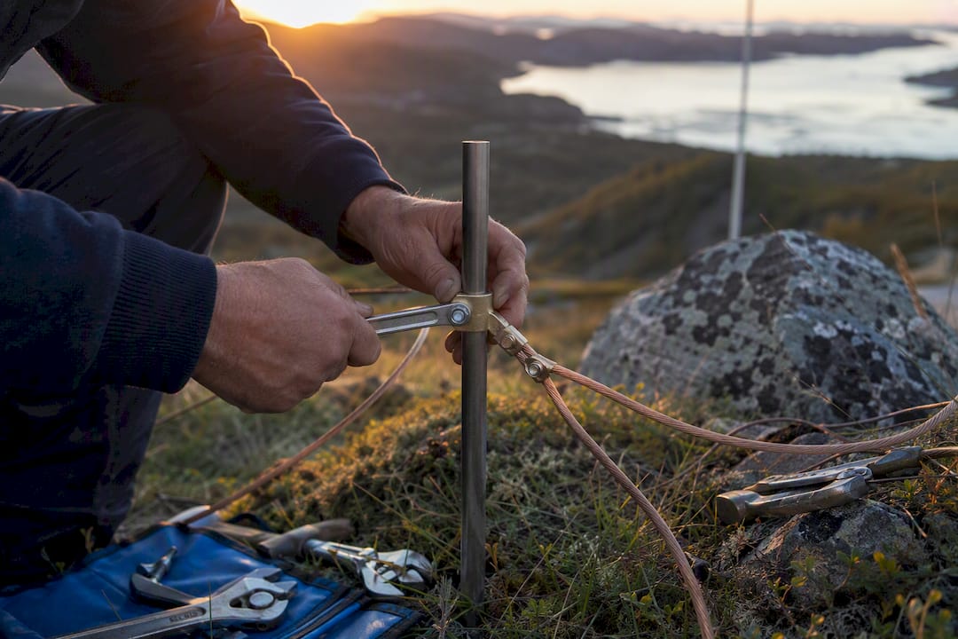 Hands installing grounding clamp on rocky ridge
