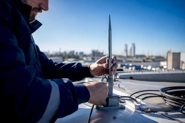 Technician installing lightning rod on rooftop