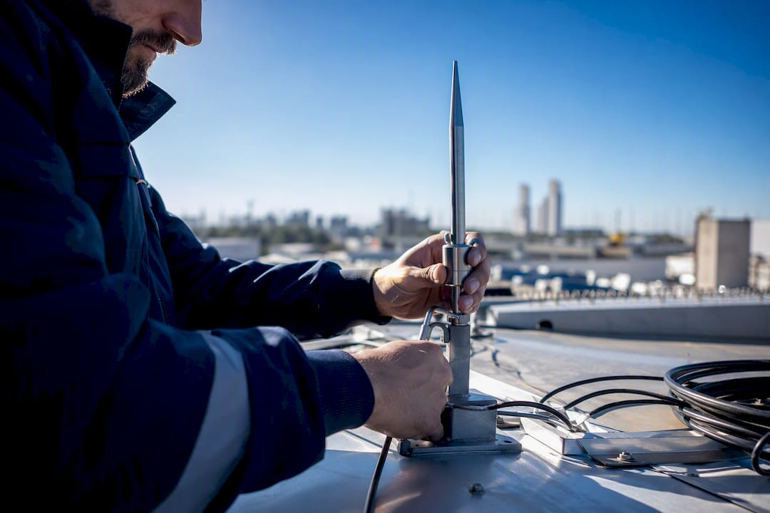Technician installing lightning rod on rooftop