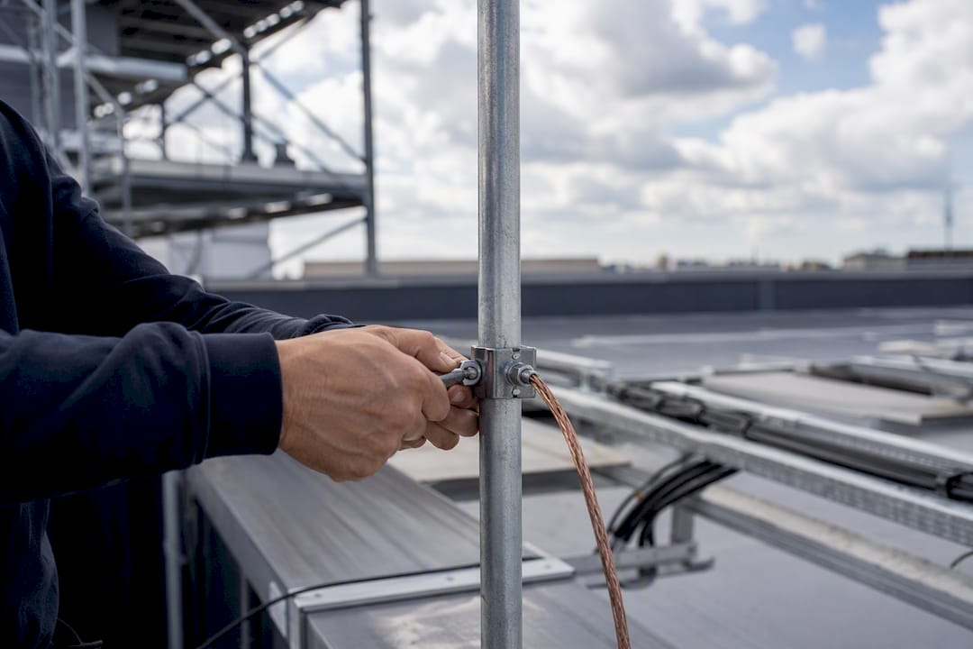 Électricien serrant une pince de mise à la terre sur un toit
