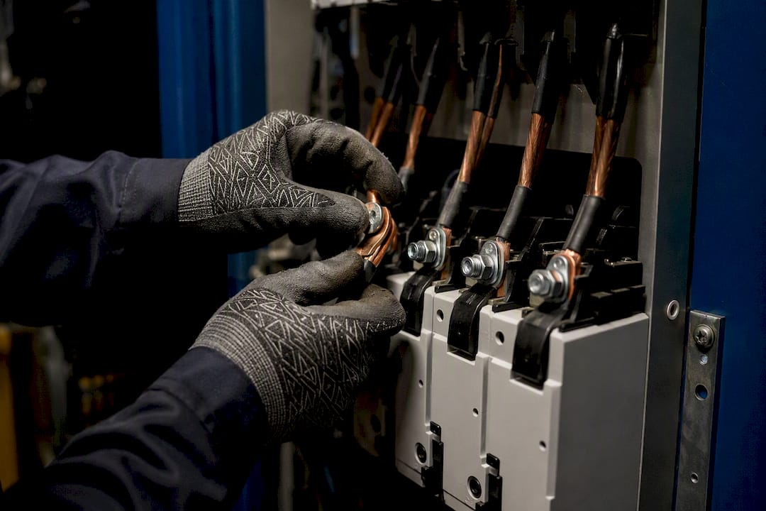 Hands wiring surge protector terminals in electrical panel