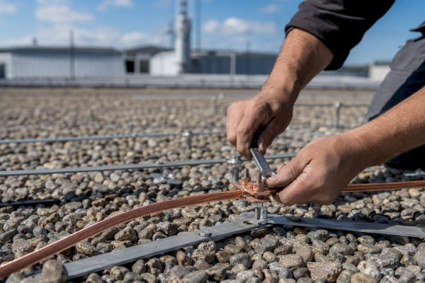Technician securing bonding conductor on rooftop