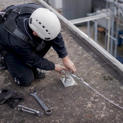 Technicien posant un point d'ancrage de sécurité sur un toit