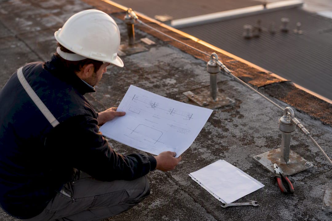 Technicien analysant les plans et la ligne de vie sur le toit