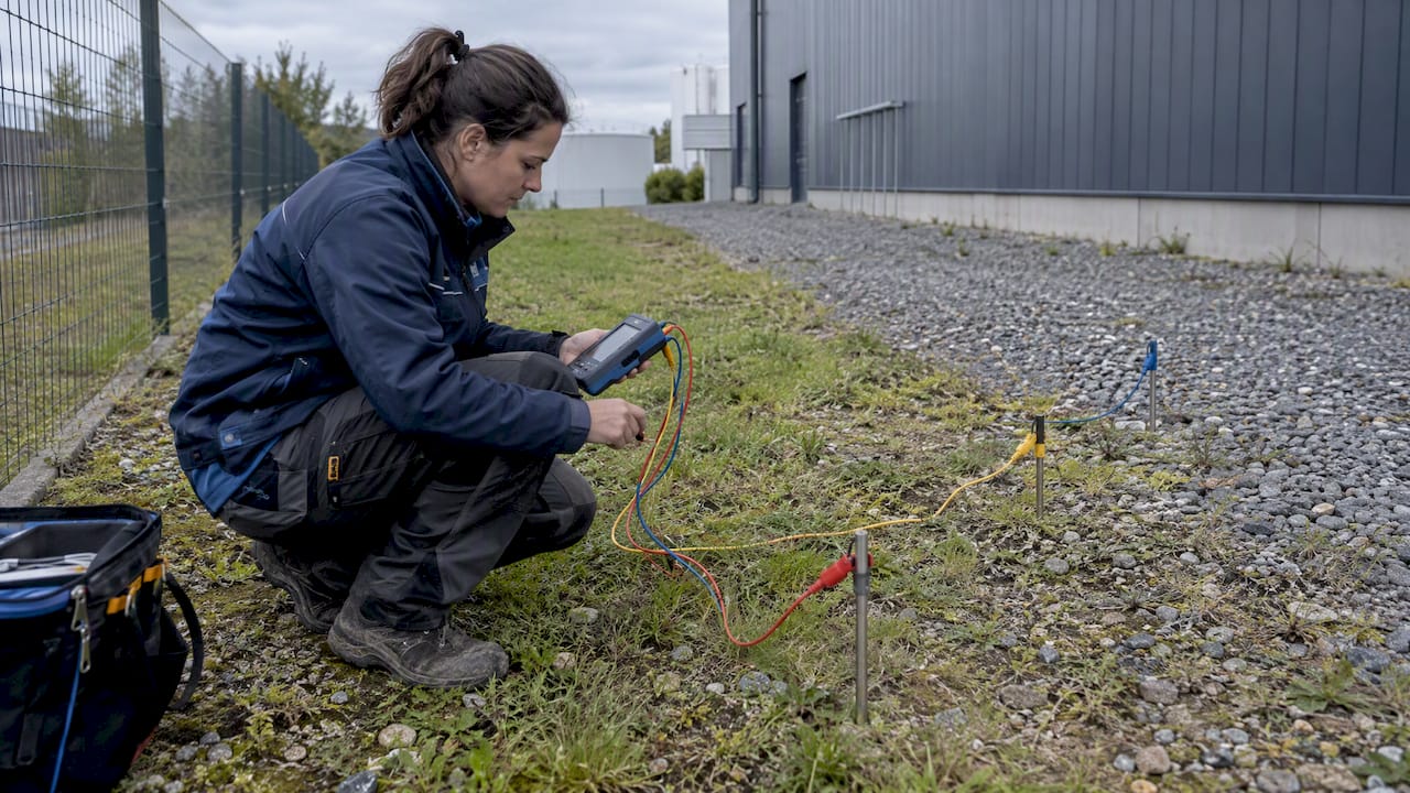 Technician measuring soil resistivity at an industrial site