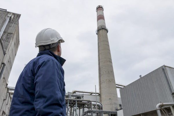 Engineer assessing a tall industrial chimney