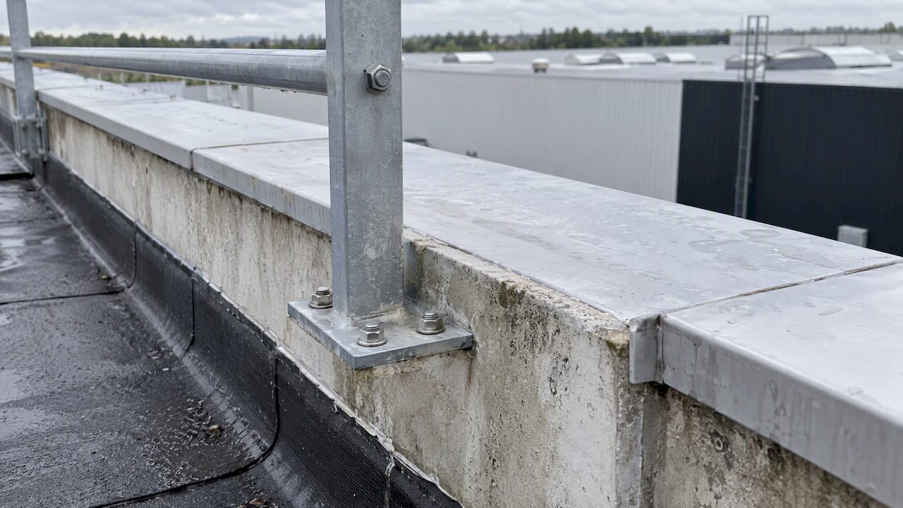 Platine de garde-corps fixée sur un acrotère en béton